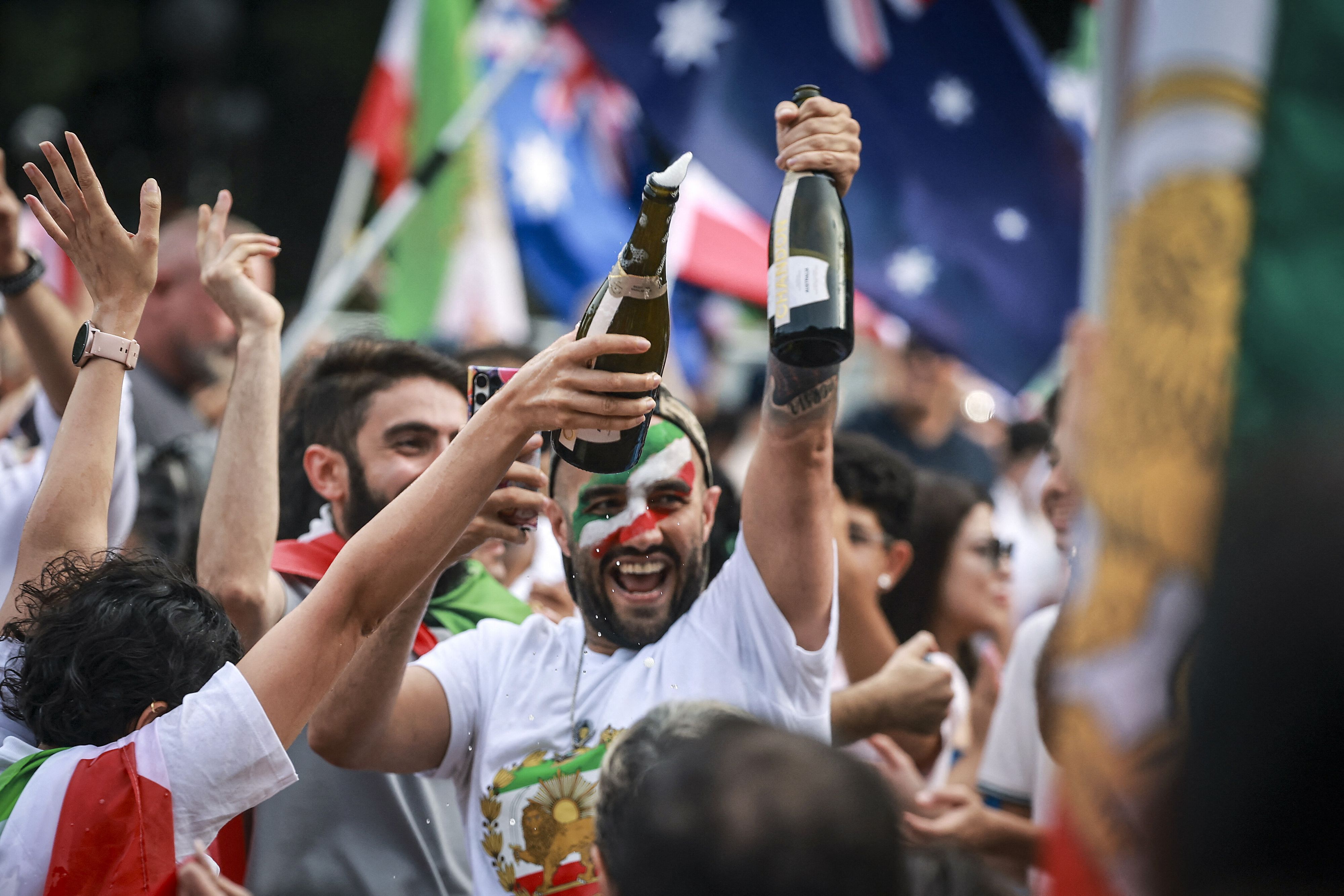 © Afp|  I membri della comunità iraniana tengono in mano bottiglie di spumante durante una manifestazione a Sydney, in Australia 