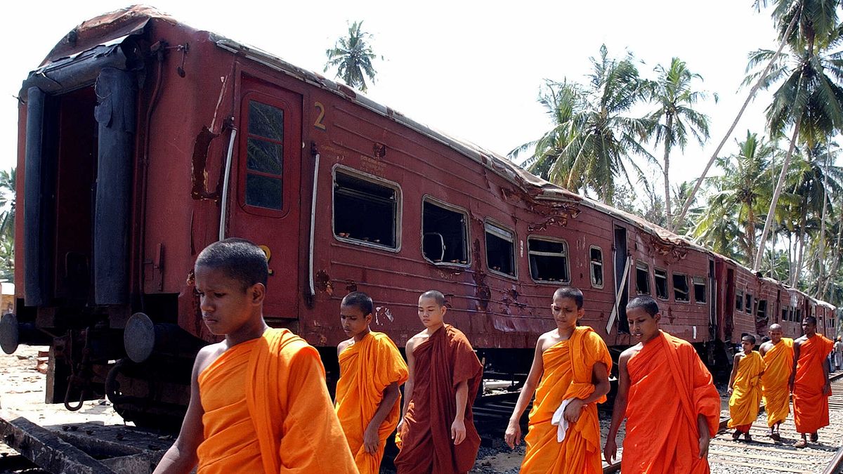 Monaci buddisti camminano davanti ai vagoni del treno colpito dallo tsunami del 26 dicembre 2004, nel villaggio di Peraliya, nel sud dello Sri Lanka