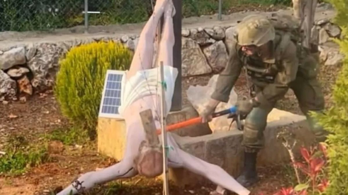 Soldato israeliano colpisce con una mazza la statua di Gesù in croce