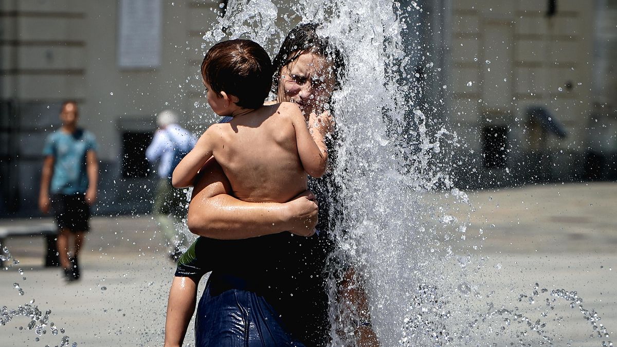 Una donna cerca refrigerio dal caldo estivo bagnandosi ad una fontana di piazza Castello, Torino 