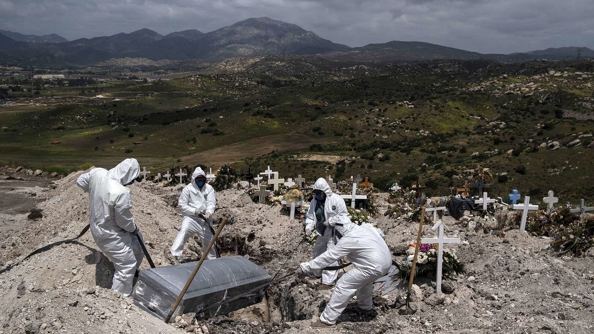 I lavoratori del cimitero che indossano equipaggiamento protettivo seppelliscono una vittima di coronavirus COVID-19 non reclamato, al cimitero municipale n. 13 di Tijuana, nello stato della Baja California, in Messico, il 21 aprile 2020. 