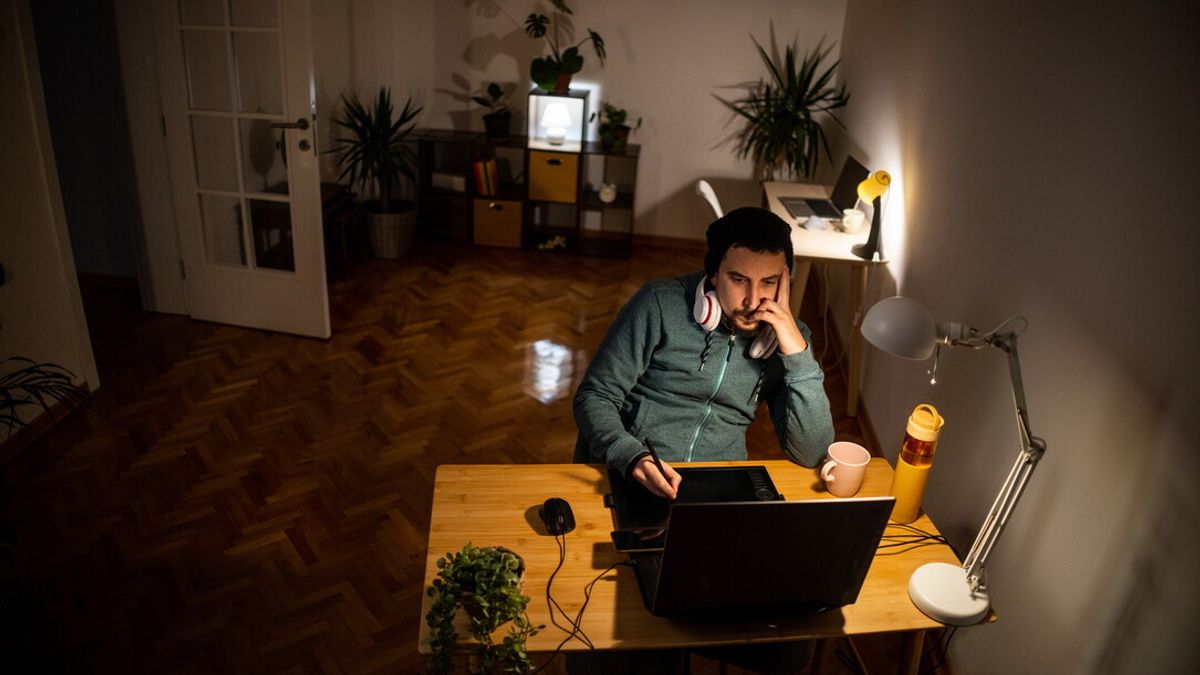 Male Caucasian student e-learning on laptop late at night