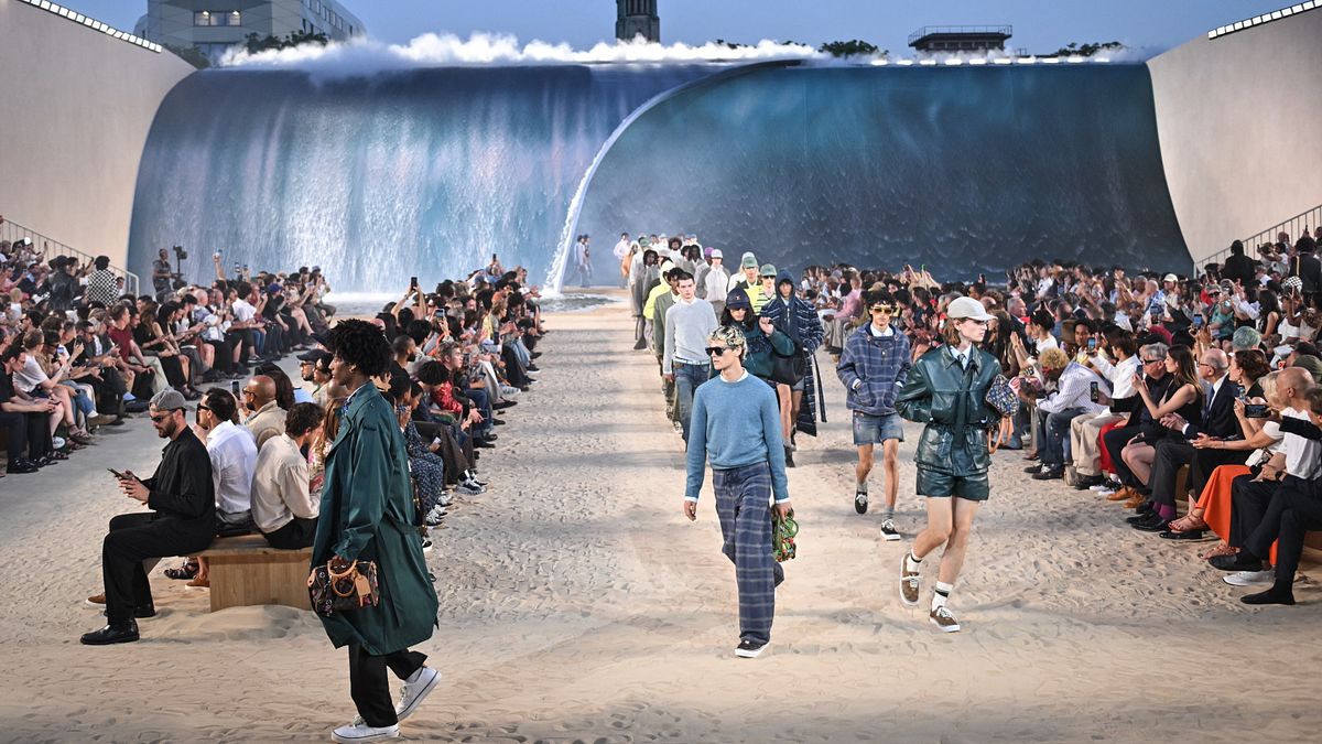 I modelli nel finale della sfilata Louis Vuitton uomo primavera estate 2027. Il set riproduceva una spiaggia di sabbia sovrastata dalle onde del mare © IPA