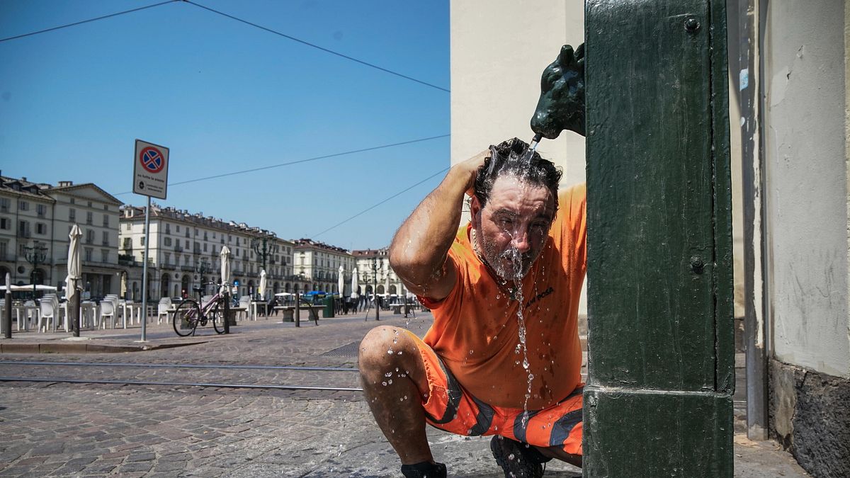 Una persona cerca refrigerio dal caldo intenso bagnandosi la testa a una fontanella, Torino © Ansa
