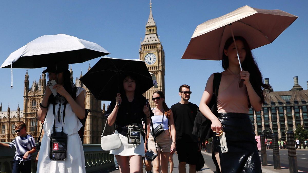 Turiste a Londra si riparano dal sole con l'ombrello © Ansa