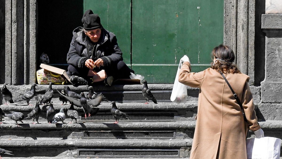 Con l'emergenza scatta la solidarietà per le persone più deboli: il 9 aprile fa il giro del web lo scatto di una signora che porge una busta della spesa a una clochard a Napoli.  © Ansa