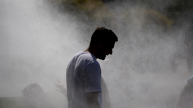 © Afp | Un uomo cerca refrigerio dal grande caldo camminando sotto un impianto di nebulizzazione a Strasburgo