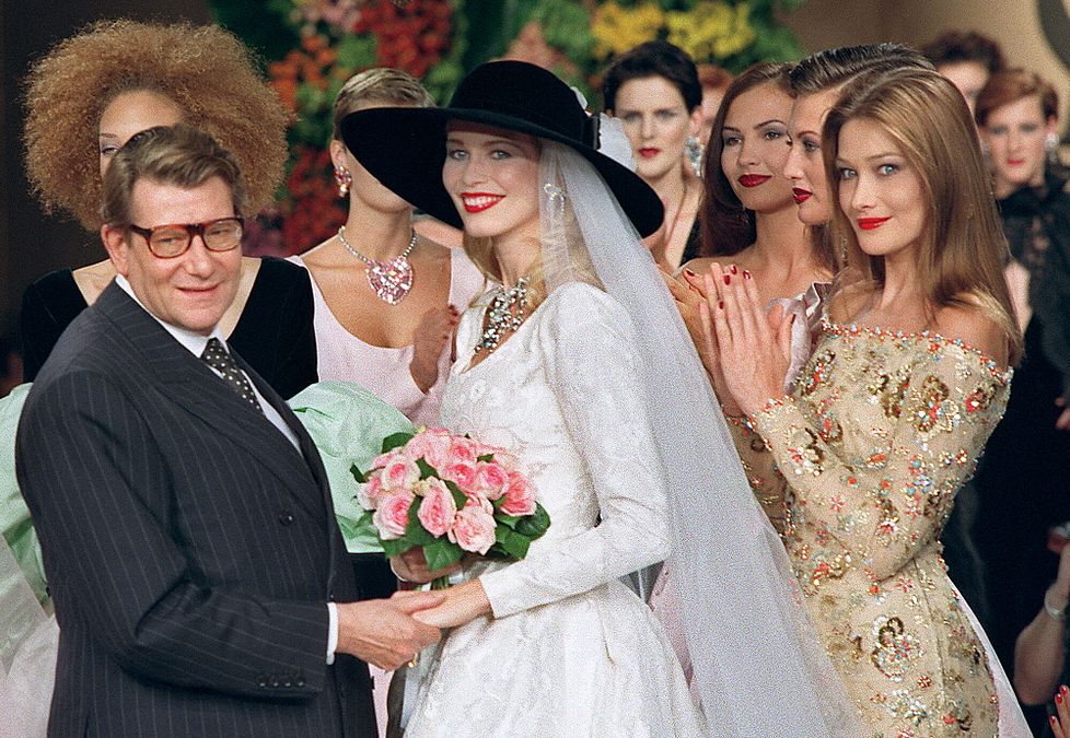 © Afp  | Yves Saint Laurent con Claudia Schiffer e Carla Bruni al termine di una sfilata nel 1996