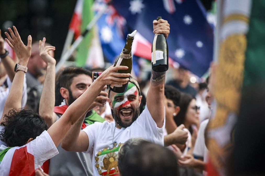 © Afp  |  I membri della comunità iraniana tengono in mano bottiglie di spumante durante una manifestazione a Sydney, in Australia 