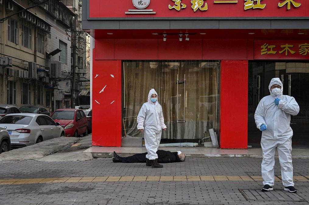 © Afp  | Questa foto scattata il 30 gennaio 2020 mostra funzionari in tute protettive che controllano un anziano che è crollato ed è morto in una strada vicino a un ospedale di Wuhan 