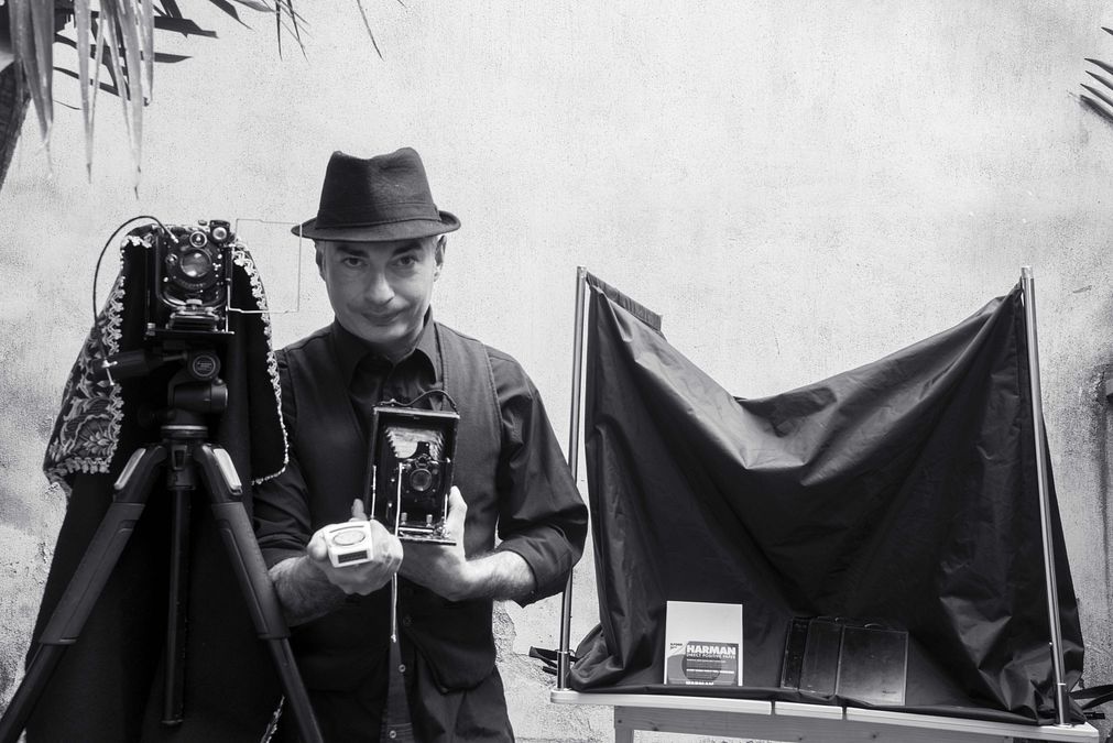 © tgcom24  | Rosario Patanè in tenuta  da lavoro con la suacamera oscura, le sue fotocamere e l'esposimetro, anch'esso del 1930