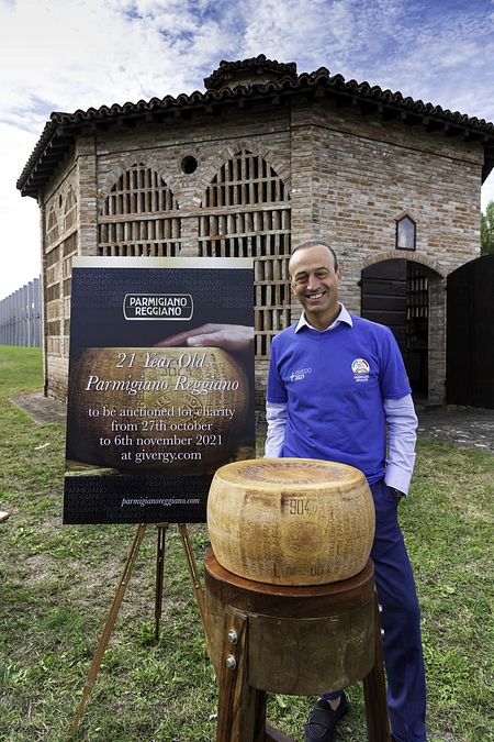© givergy.uk  | Nicola Bertinelli (presidente del Consorzio del Parmigiano Reggiano) con la forma che va all'asta
