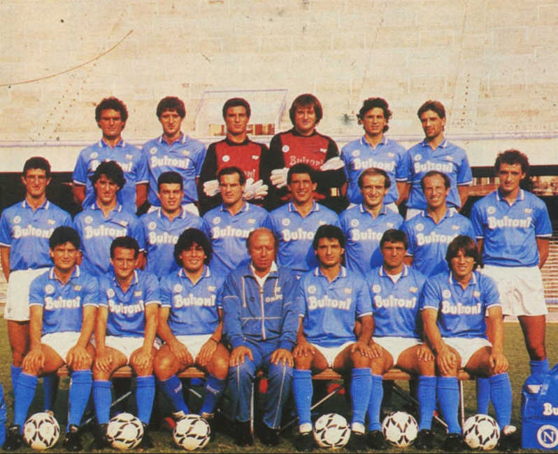 © Wikipedia  | La rosa del primo, storico, scudetto del Napoli vinto nel 1986-1987. Da sinistra, in alto: Bruscolotti, Bigliardi, Di Fusco, Garella, Carnevale, Filardi; al centro: Ferrara, De Napoli, Carannante, Volpecina, Bagni, Ferrario, Sola, Renica; in basso: Muro, Celestini, Maradona, Bianchi (allenatore), Caffarelli, Giordano, Puzone.