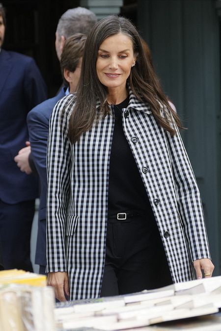 © IPA  | Lo stile di Letizia di Spagna: cappottino leggero Vichy, tracollina nera e scarpe Mary Jane per la sua visita alla Cuesta de Moyano, la fiera permanente del libro di Madrid