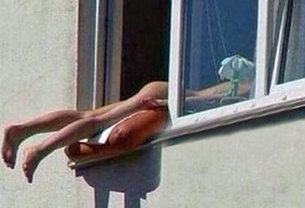 Donna russa si abbronza fuori dalla finestra creando scompiglio