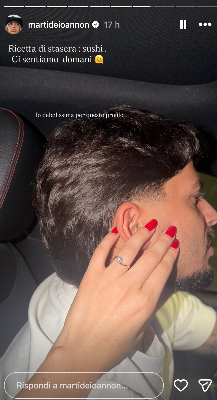 Close-up of a woman’s hand with red nails and a diamond ring resting on a man’s temple inside a car; text overlay reads: 'Ricetta di stasera: sushi. Ci sentiamo domani.'