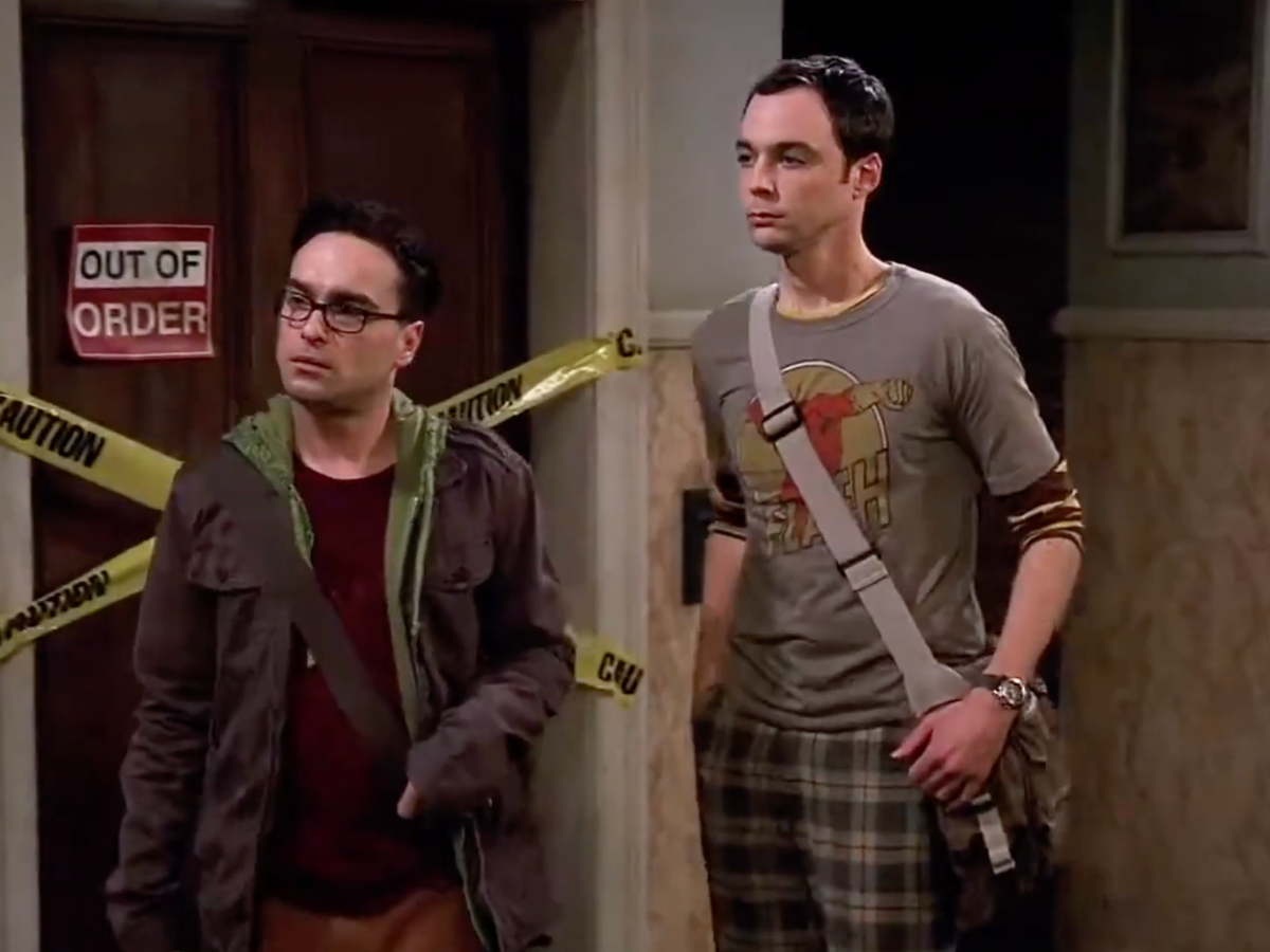 Two men stand in a doorway with yellow caution tape and an 'Out of Order' sign behind them.