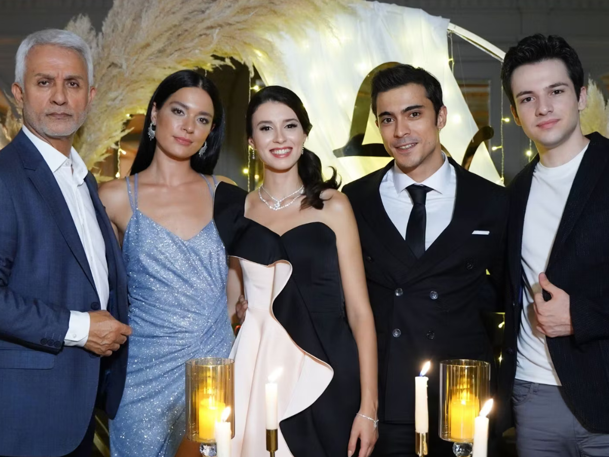 Group of five adults dressed formally posing at a gala with candlelit decor in the background.
