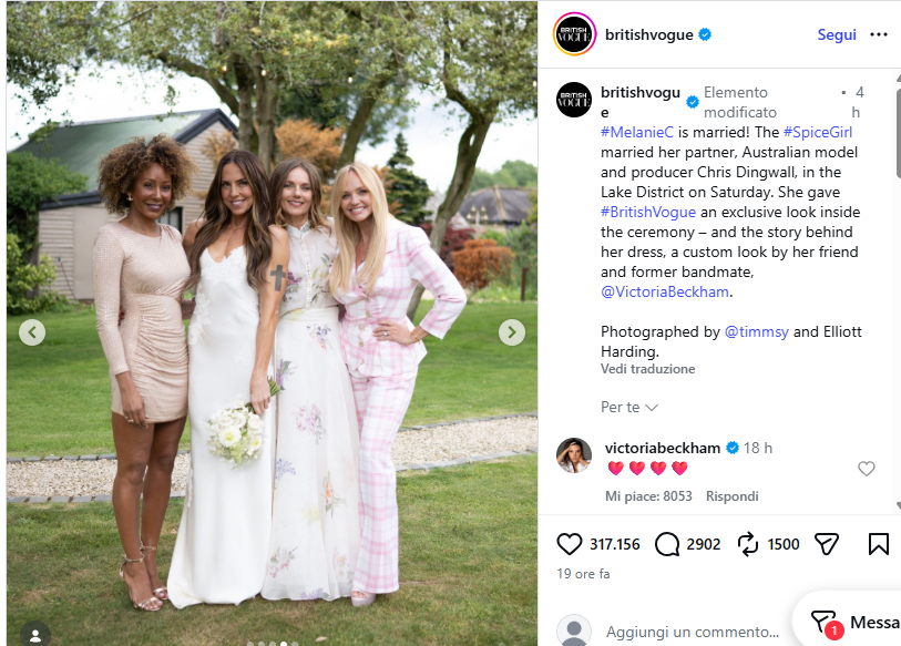 Four women in wedding dresses posing together outdoors on a grassy garden, one in a white bridal gown holding a bouquet, all smiling.
