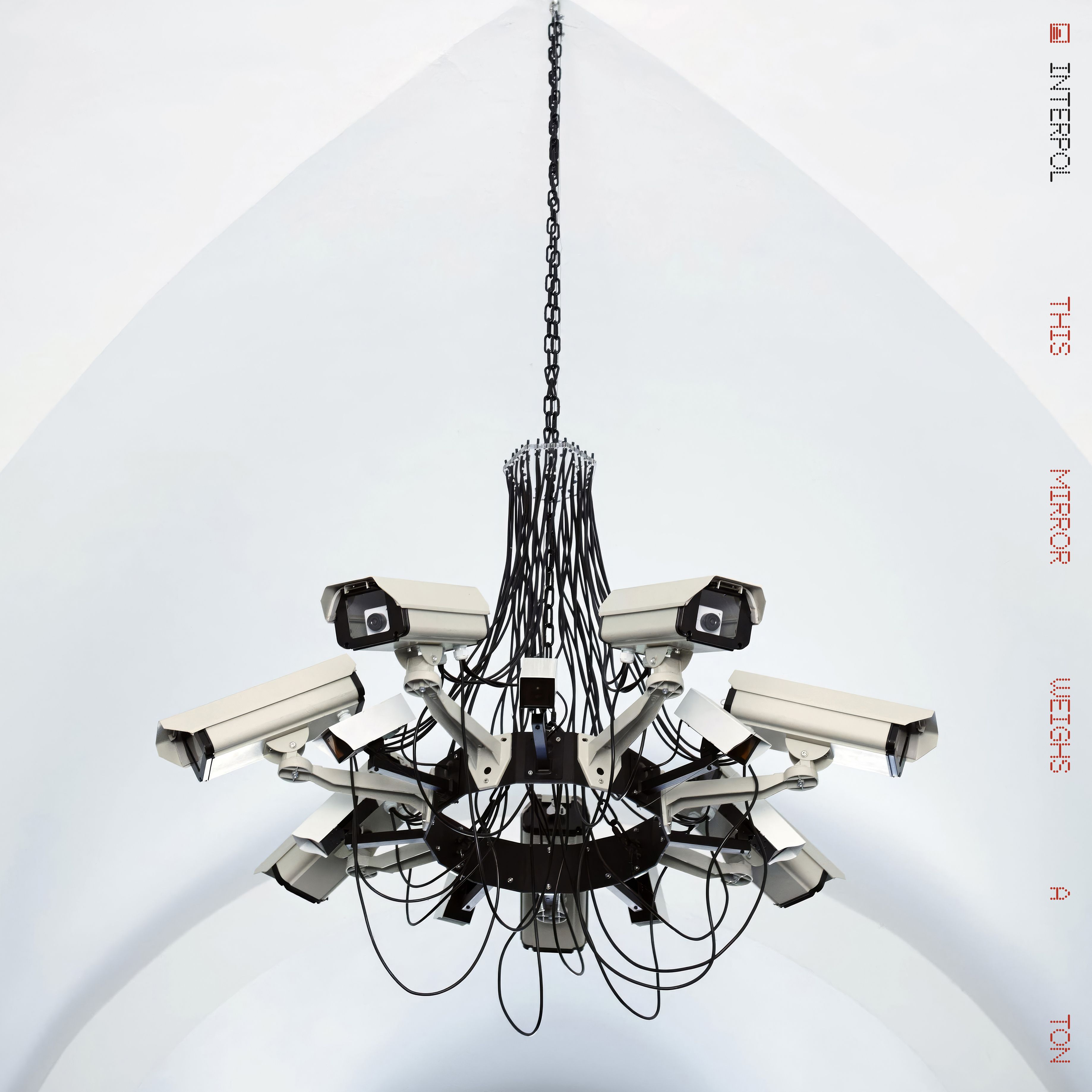 Chandelier-like fixture with many black cables and metal arms hanging from a white ceiling.