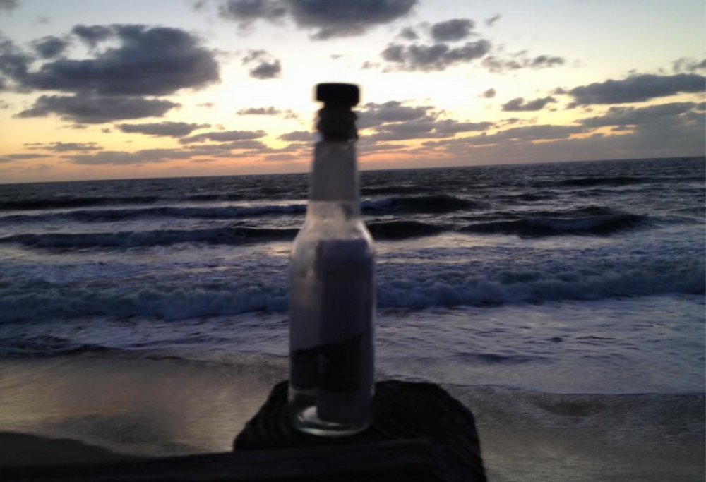 Un uomo trova una bottiglia sulla spiaggia